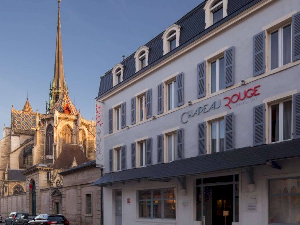 Chapeau Rouge hotel and a church with a colorful tiled roof.