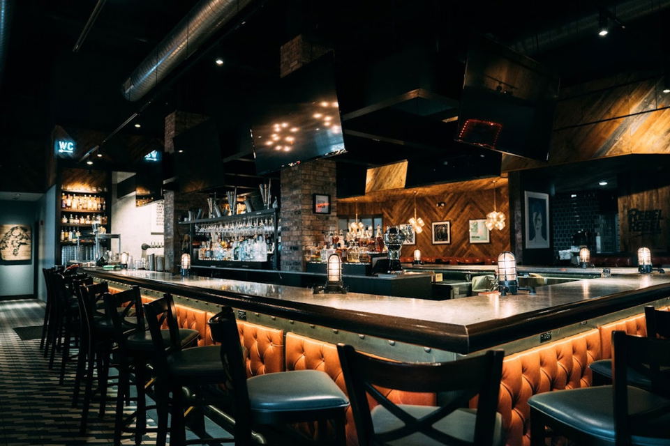 An overhead shot of a person cutting into a dish at Cadence restaurant, surrounded by other plated dishes and a glass of rosé.