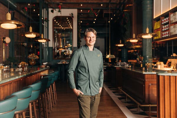 A man stands in a restaurant with a bar and seating