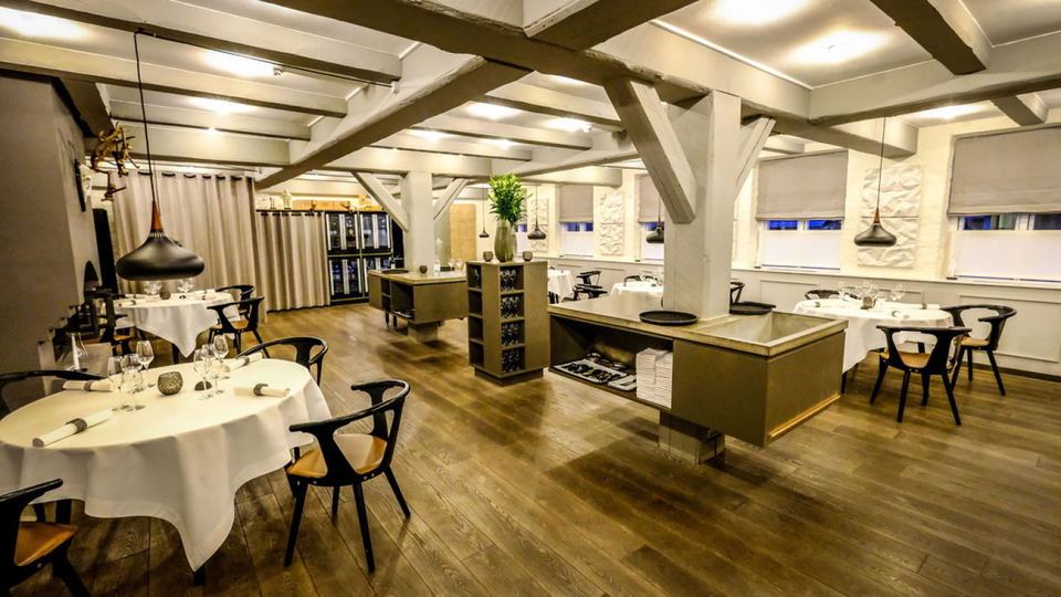 Elegant restaurant interior with tables, chairs, and exposed wooden beams