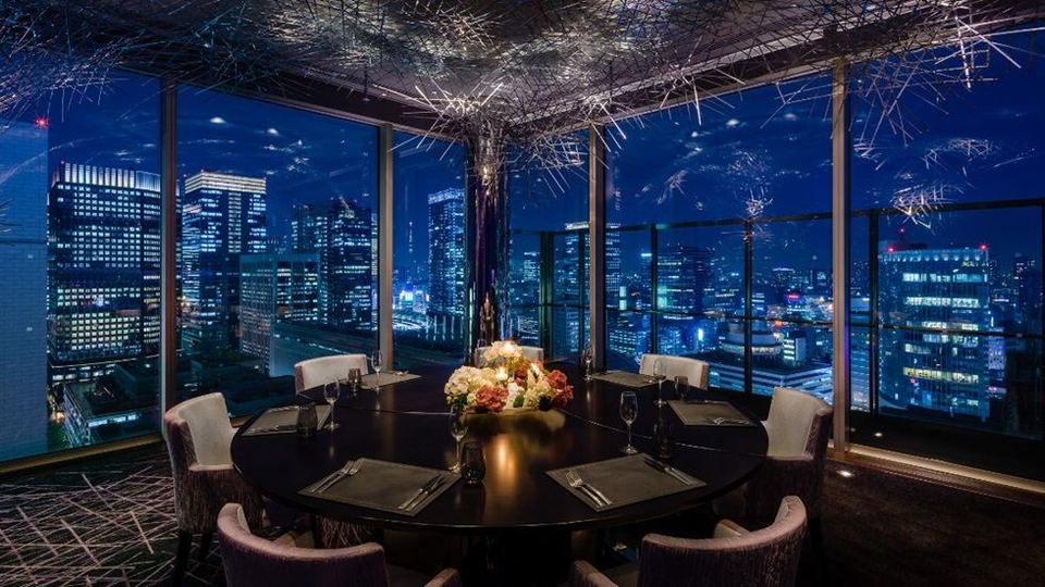 Elegant dining room with city skyline view at night.