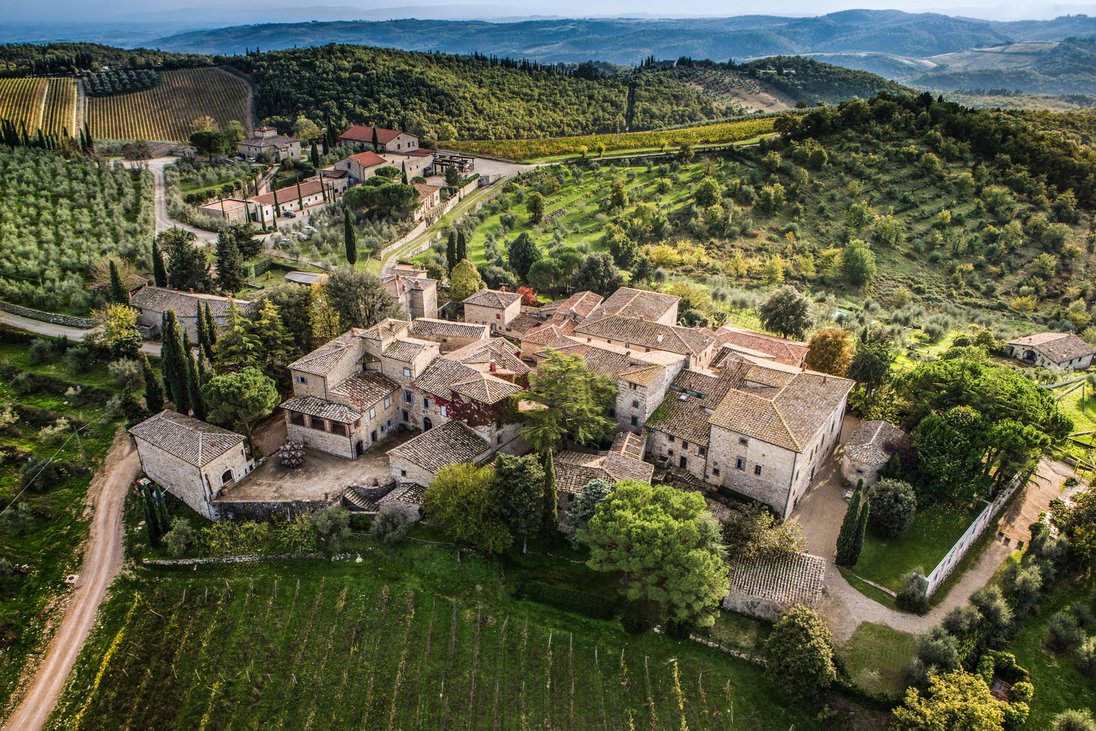 Aerial view of a Tuscan village surrounded by vineyards and olive groves.