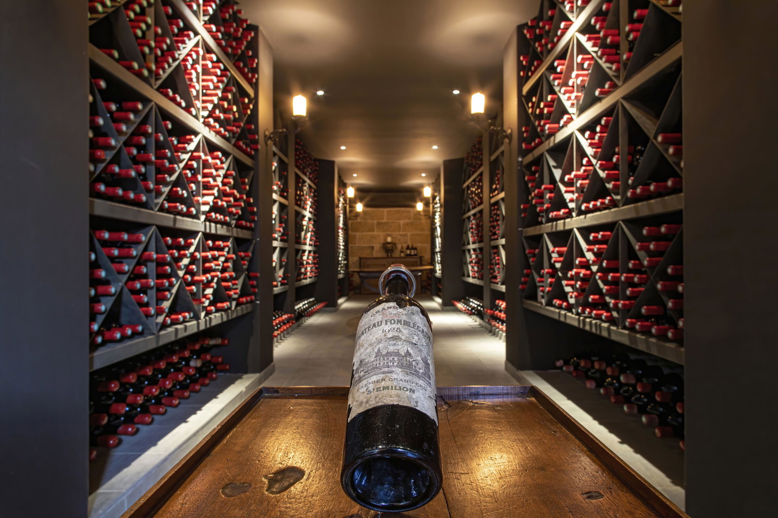 A professional wine cellar with extensive bottle storage in diamond-bin racks, featuring a single vintage Bordeaux bottle (Château label visible, Prem
