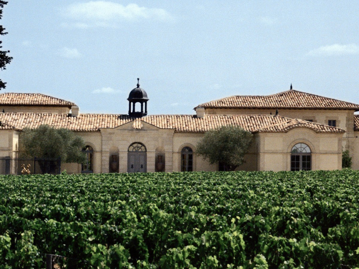The Pétrus estate in Pomerol, Bordeaux, showing the modest stone chai building with its distinctive central cupola and terracotta roof tiles.