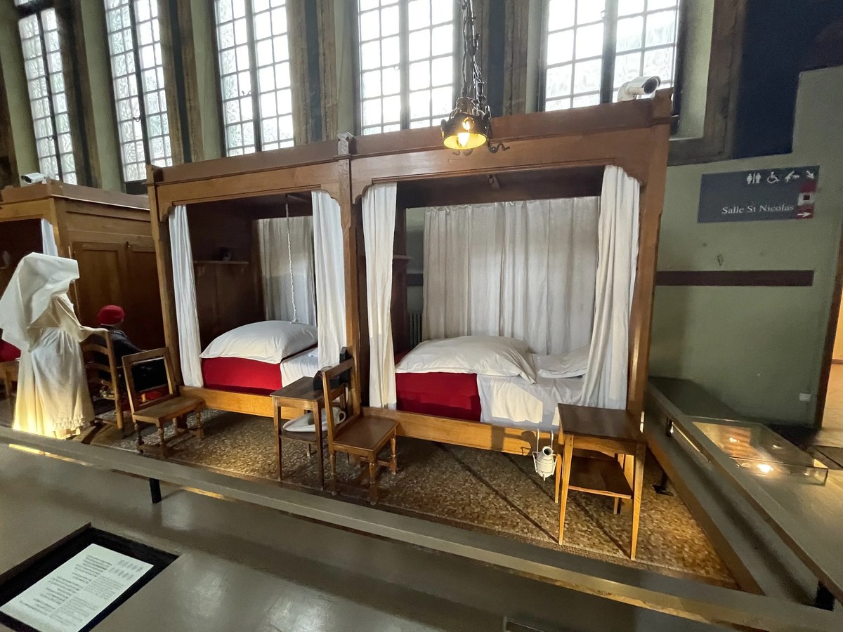 Hôtel-Dieu interior museum: Historic hospital ward beds with canopied wooden frames and red bedding.