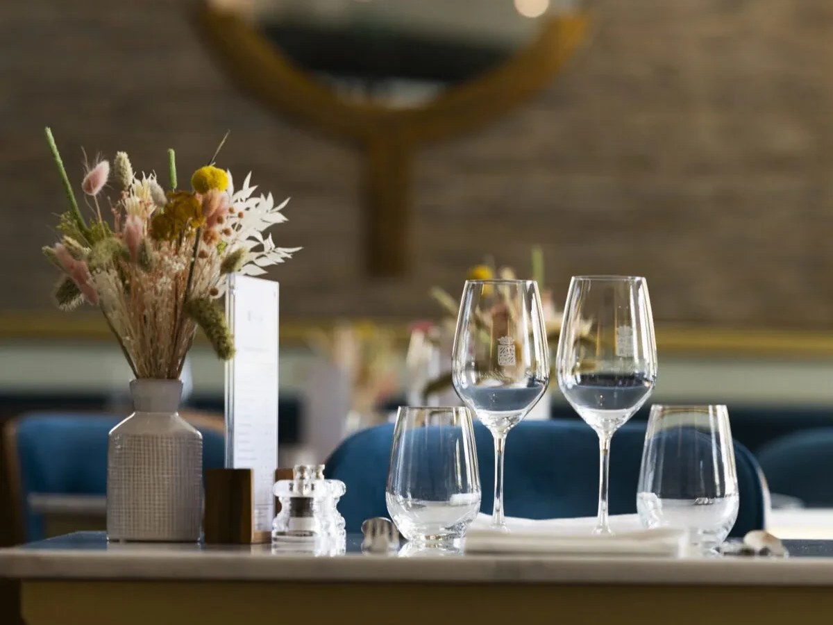 Table setting with glassware, a vase of dried flowers, and a menu.