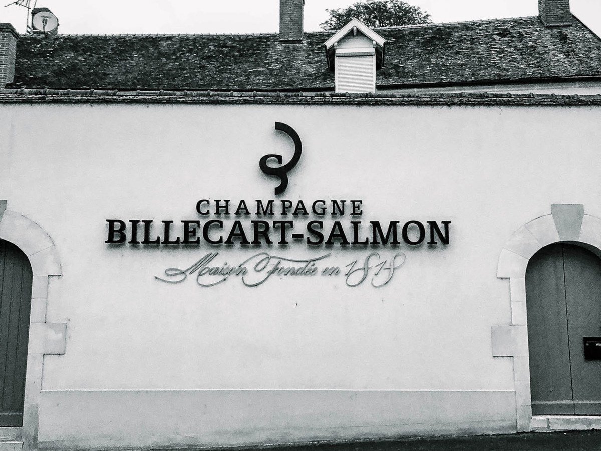 A black-and-white photo shows the exterior of the Billecart-Salmon champagne house, with its name and founding year on the facade.