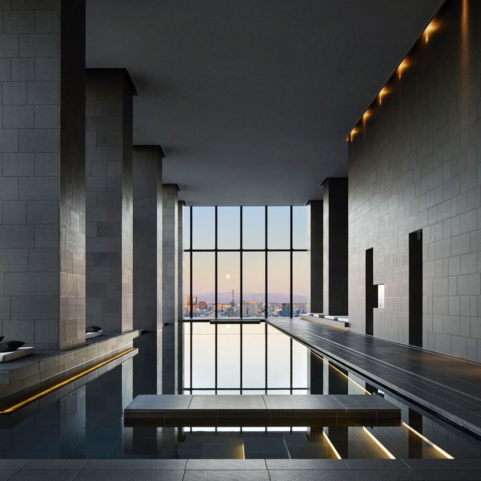 A modern Japanese-style spa bathing area with dark tile walls, reflective water features, dramatic columns, and a large window overlooking a city skyl