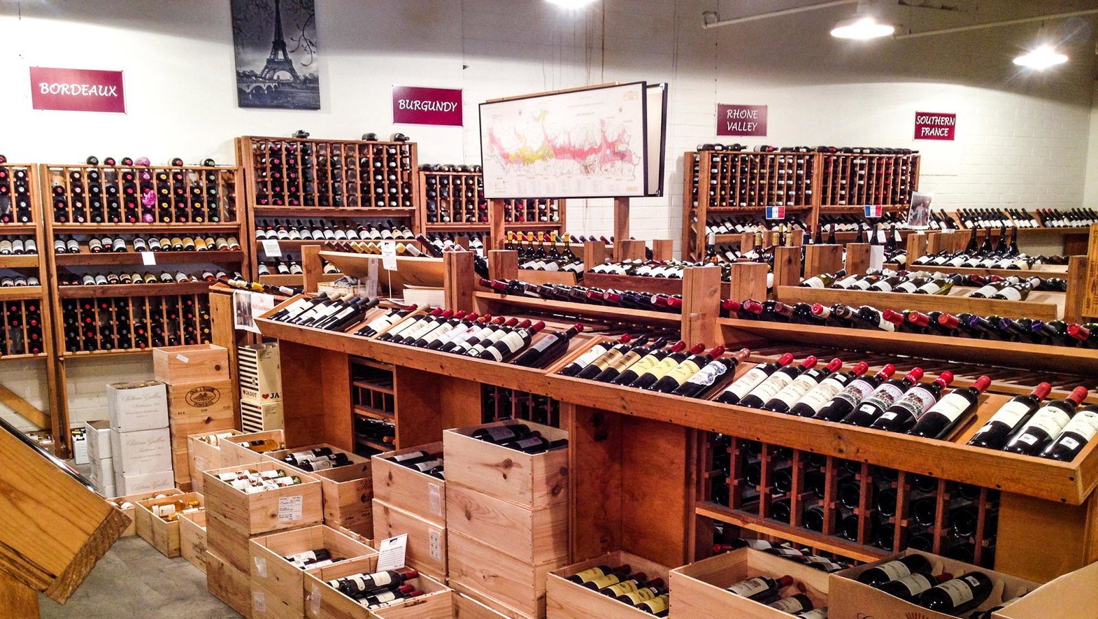 The Wines are neatly arranged in rows on wooden shelves and stacked in crates throughout the space.