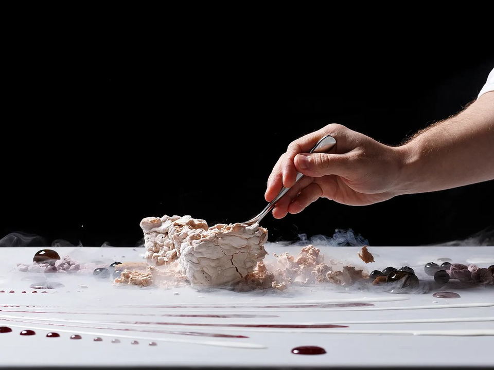 Alinea: A chef cracks open a frozen dessert, surrounded by berries, sauce, and dry-ice smoke.
