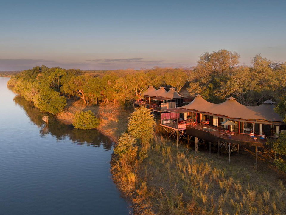 Anantara Tented Camp Kafue River at sunset, an aerial view of the elevated camp along the river.