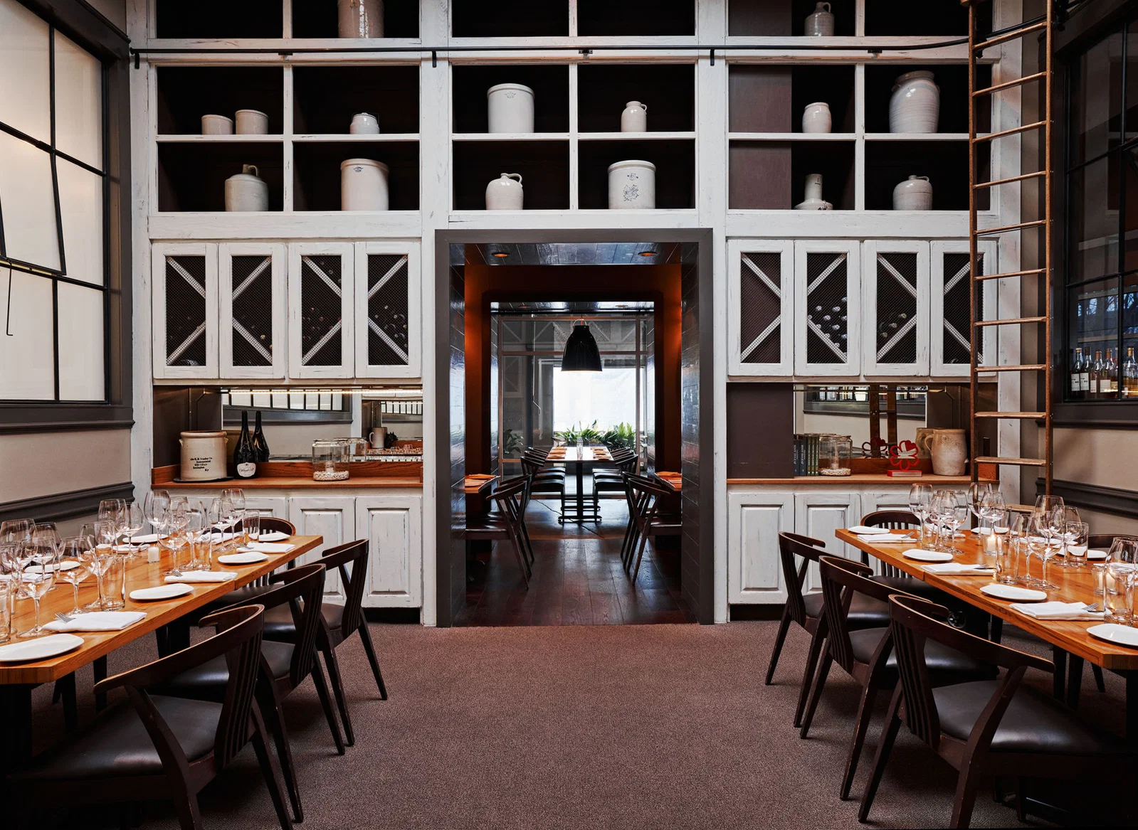 The interior of Miller Union, a restaurant with two long wooden tables set with wine glasses and plates, dark wooden chairs, and a central archway