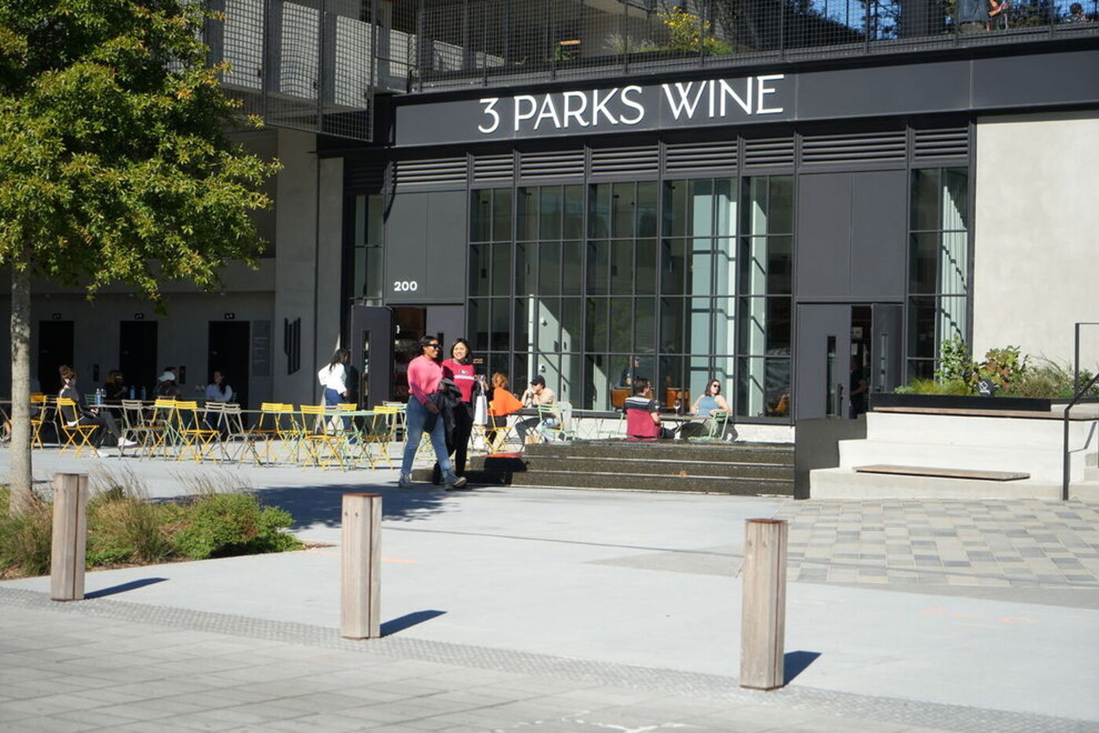 The exterior of 3 Parks Wine, a wine shop in Atlanta, with people seated at outdoor tables and walking by on a sunny day.