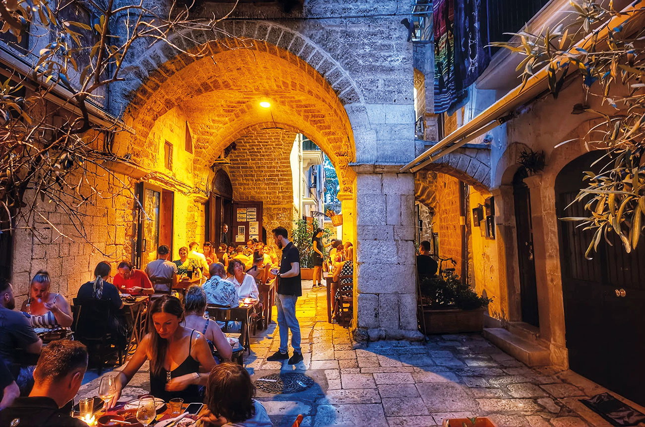 Enoteca Cucumazzo (Bari) glows with warm, inviting light under its ancient stone archway.
