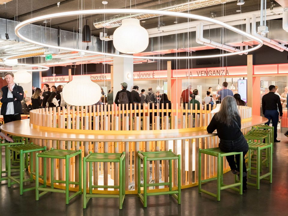 Saluhall's Market Street buzzes with diners at its communal table and diverse vendor stalls.