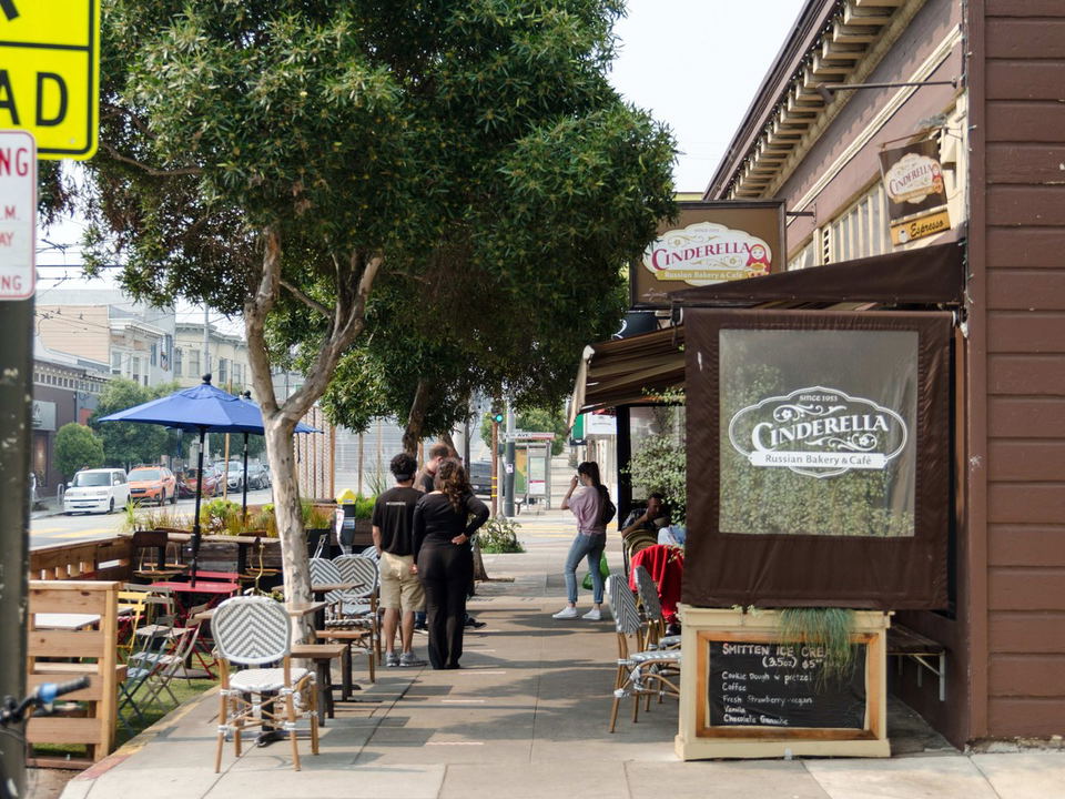 Exterior sidewalk view of Cinderella Russian Bakery & Café with visible signage, outdoor seating, and a chalkboard menu.
