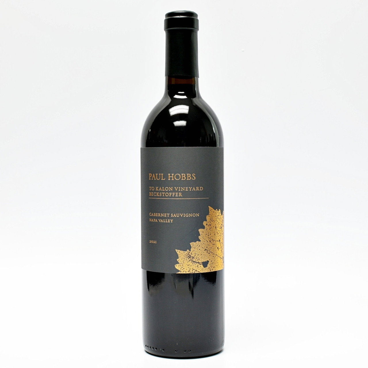 A Paul Hobbs Beckstoffer To Kalon Vineyard Cabernet Sauvignon 2021 wine bottle, with a black label and golden leaf design.