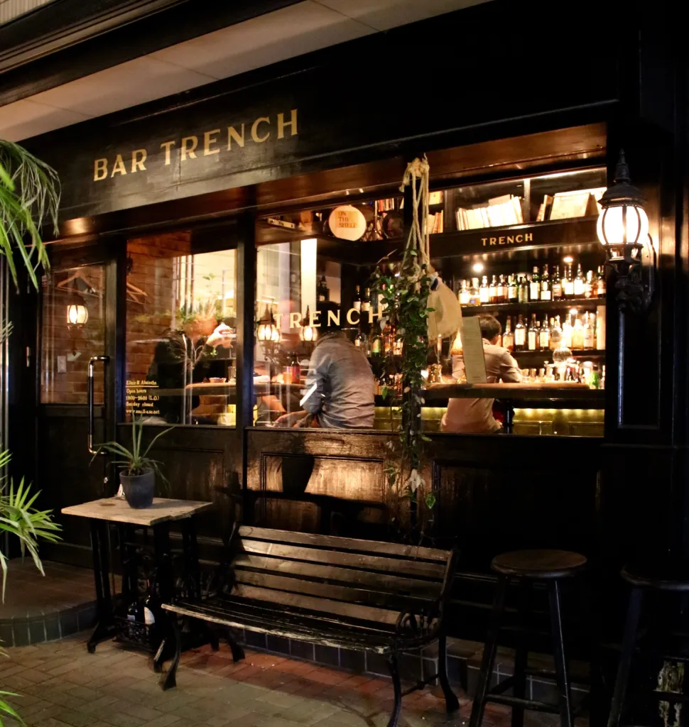 5. Bar TRENCH (Ebisu) features a cozy wooden bench and table outside its inviting entrance.