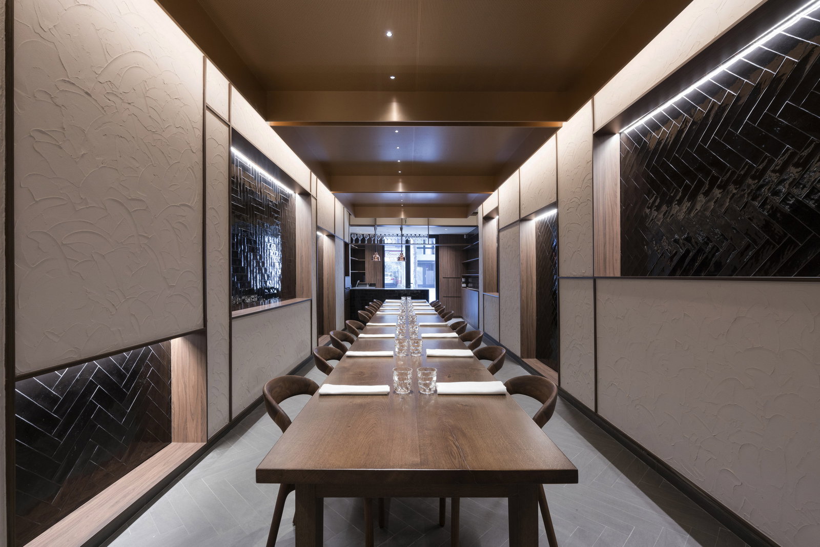 6. Cinc Sentits highlights dark, glossy herringbone tiles illuminated by sleek strip lighting.
