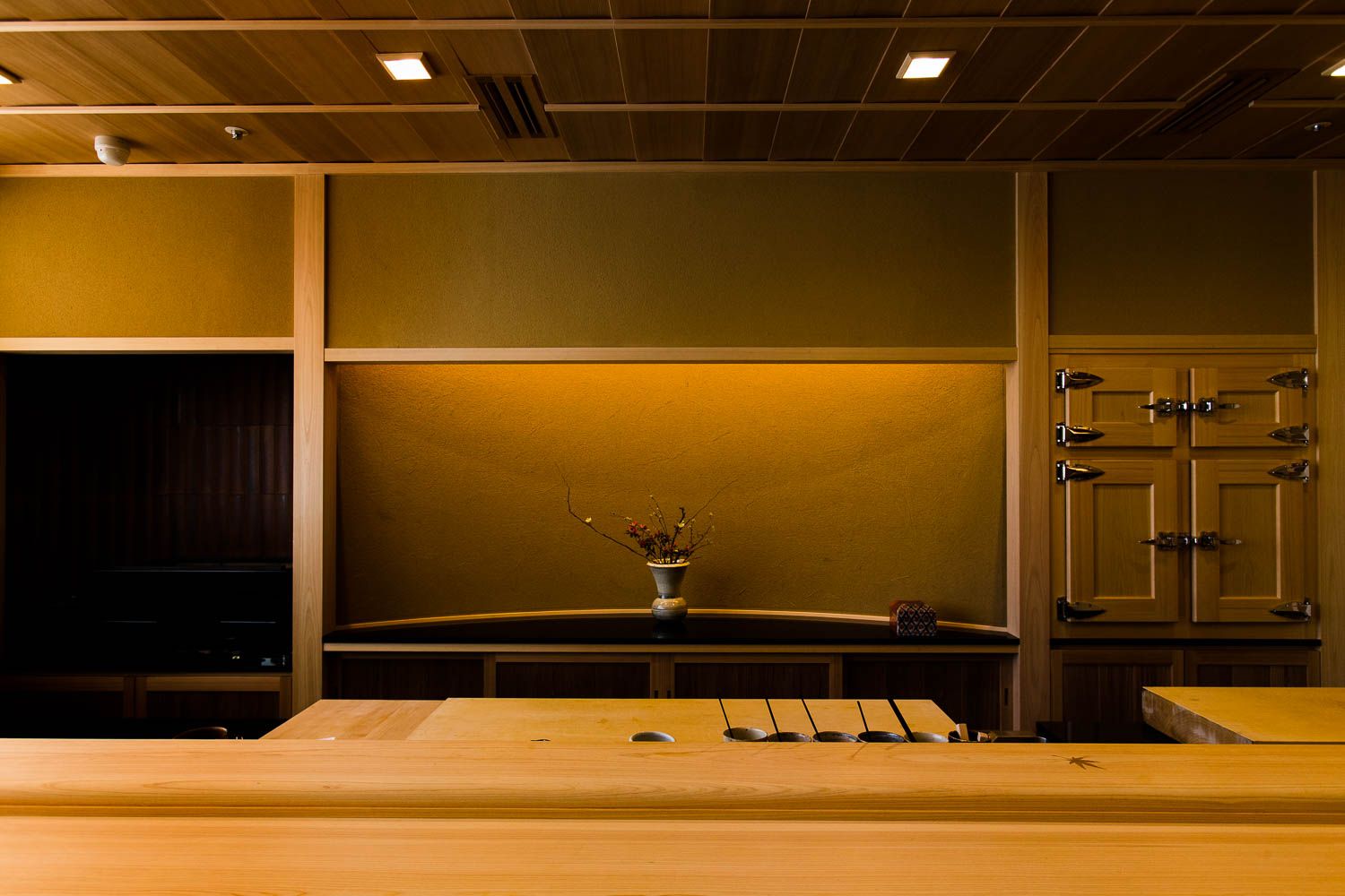 9. Sushi Yoshitake features a warm, golden-hued wall providing a serene backdrop to the dining area.
