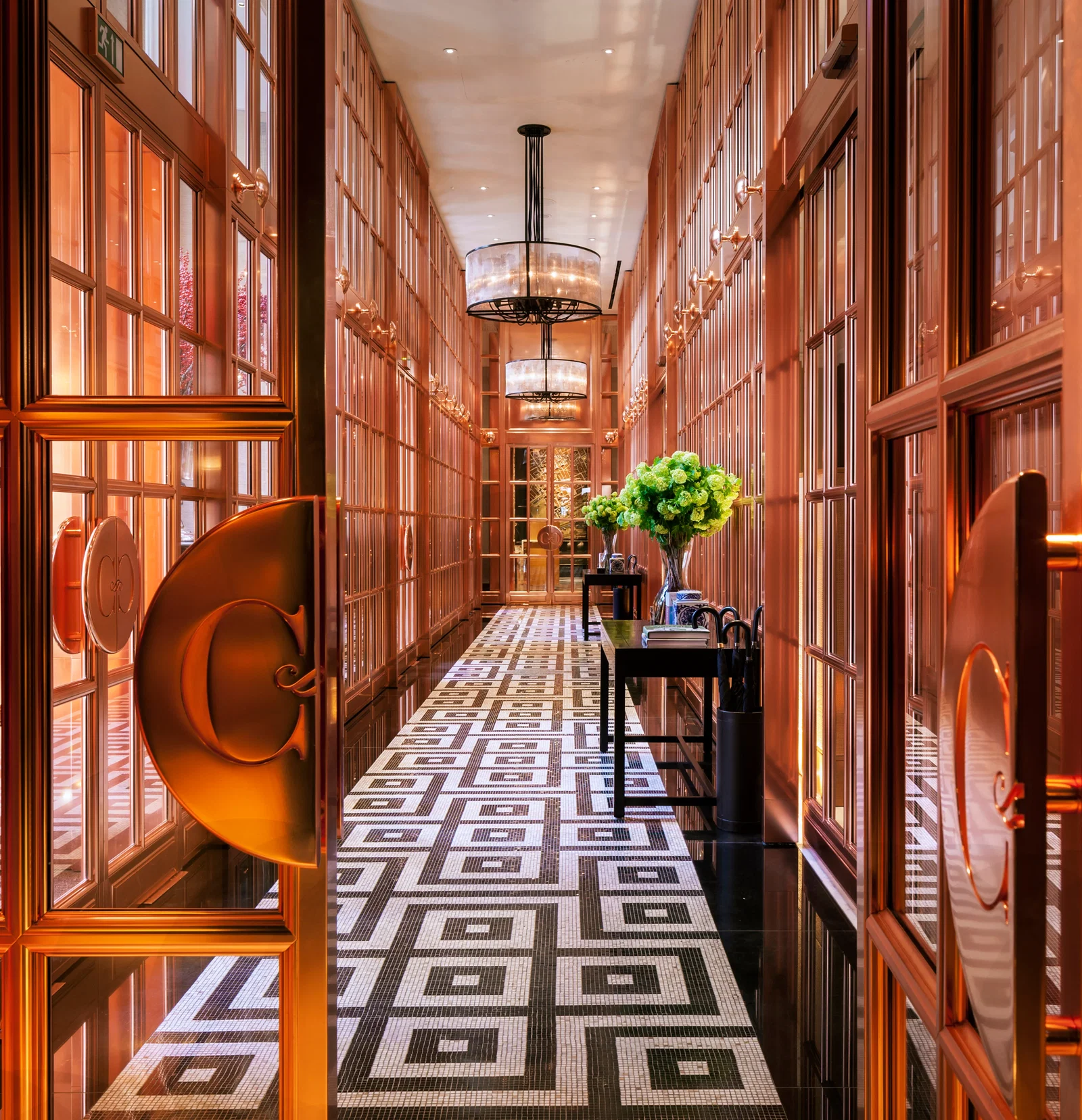 8. Rosewood London's corridor gleams with warm, reflective copper-toned paneling and frames.