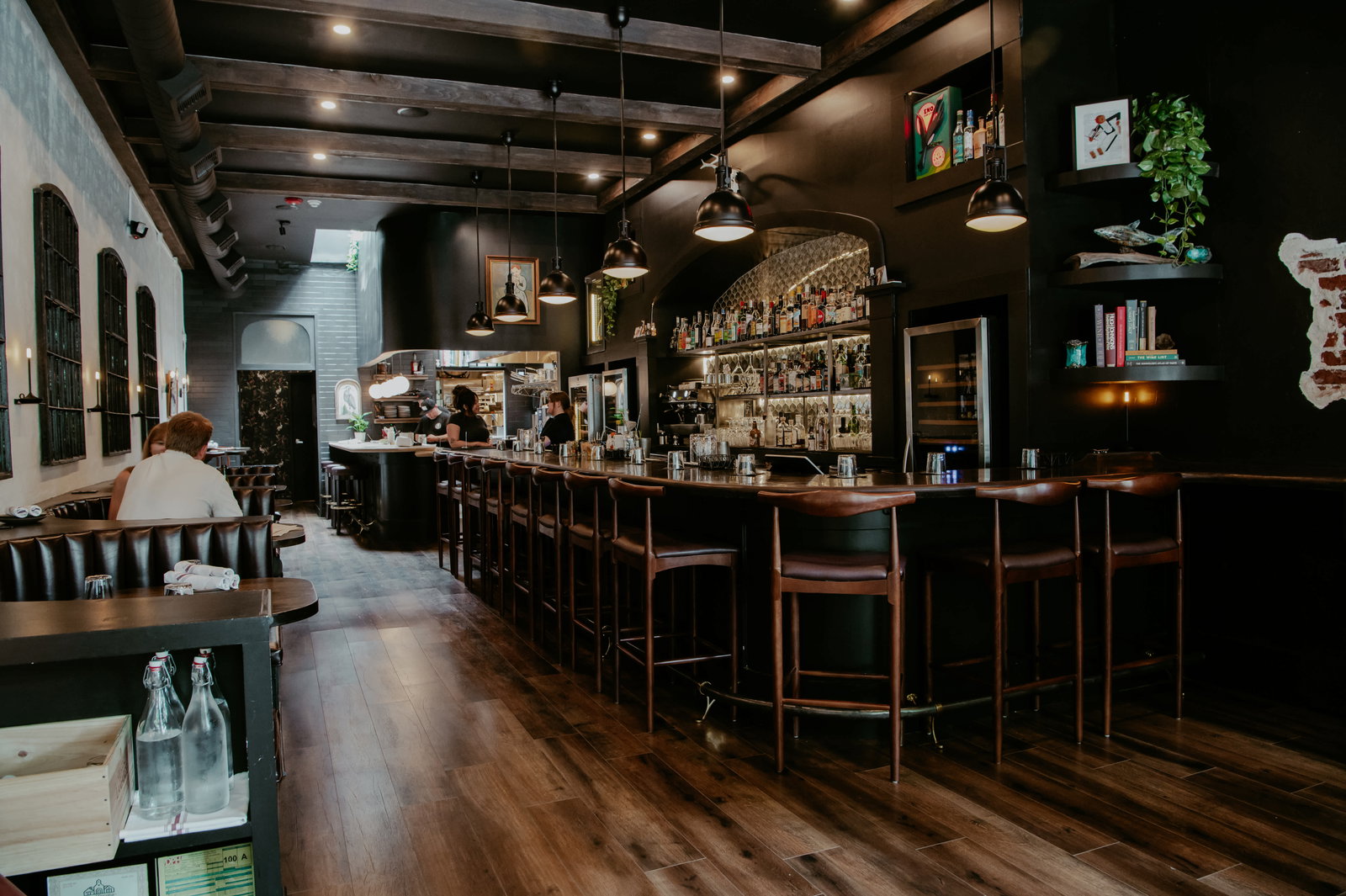 The cozy, maritime-inspired interior of Fawn Wine and Amaro in Decatur, Atlanta, with a bar lined with amaro bottles, soft pendant lighting, and seafood-focused menu boards.