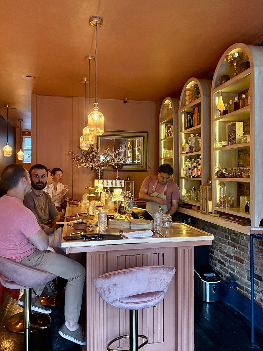 Beyond Proof (Jamaica Plain), featuring a distinctive warm terracotta-pink color scheme throughout the space.
