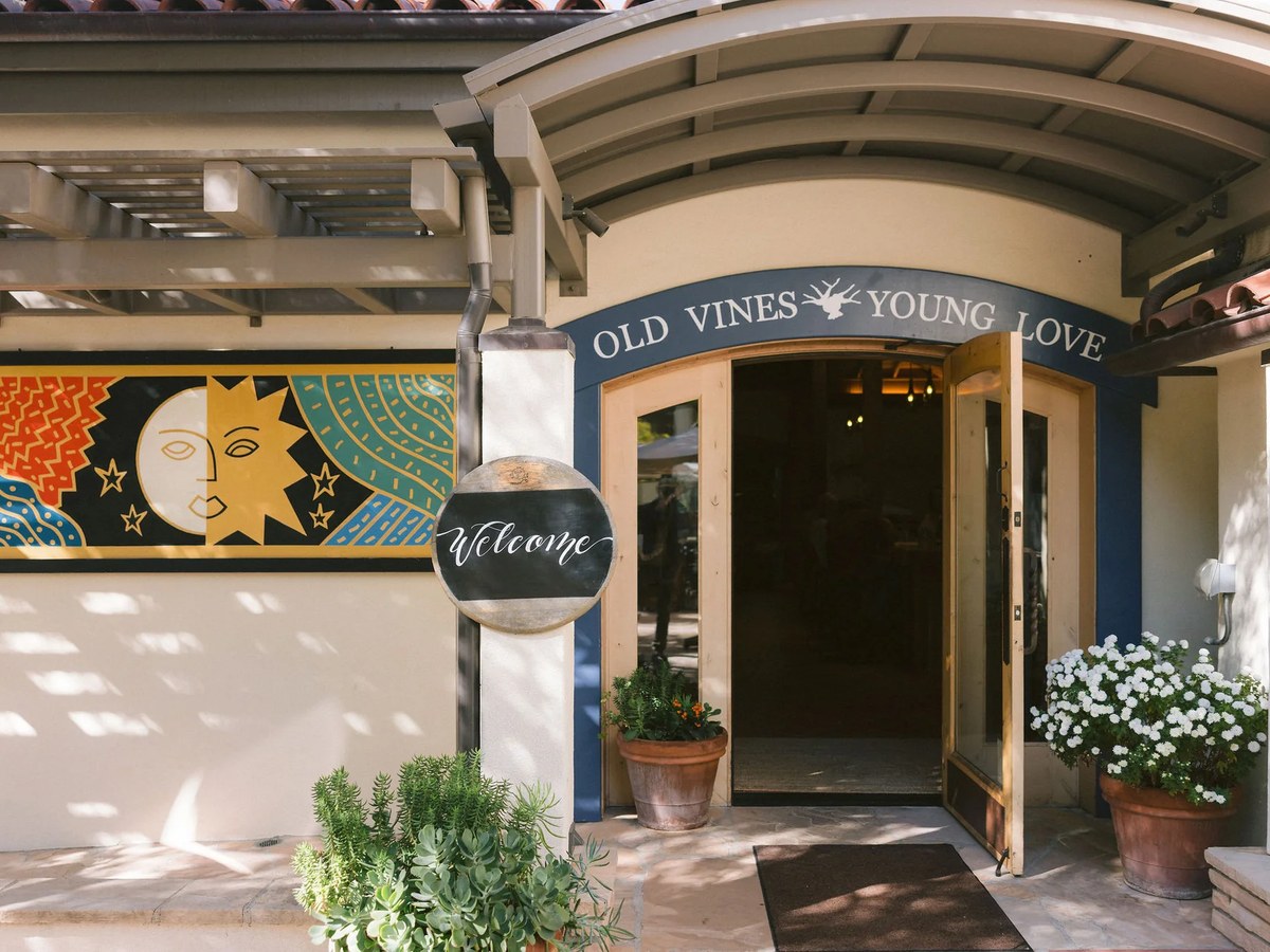 Entrance to a winery tasting room with 'OLD VINES YOUNG LOVE' signage and a 'Welcome' sign.