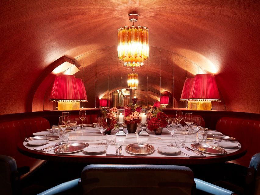 Elegant dining room with red decor, chandeliers, and a set table