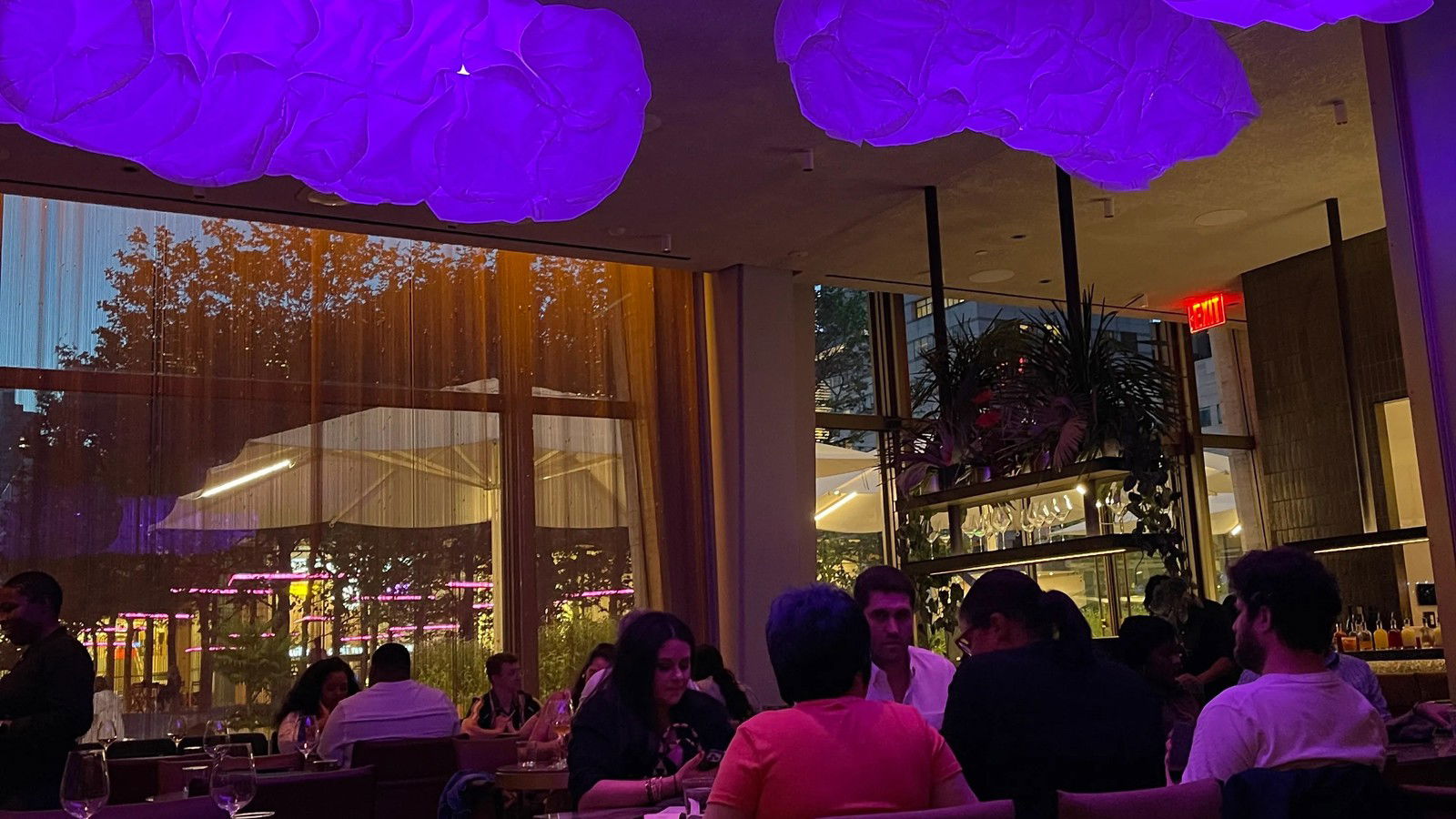 The main dining room of Tatiana by Kwame Onwuachi at Lincoln Center, illuminated by purple cloud-like lights.