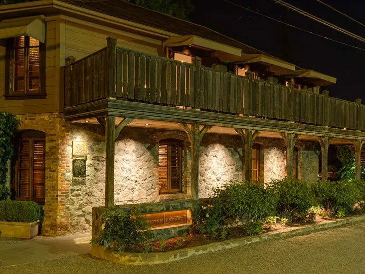 The French Laundry's rustic stone and wood exterior glows under the night sky.