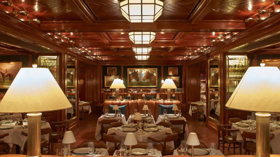 The Polo Bar's subterranean main dining room, with dark wood, leather banquettes, equestrian prints, and brass.