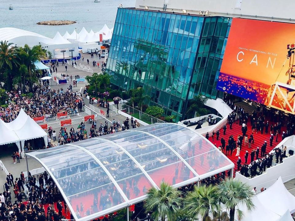 Cannes Film Festival buzzes with crowds along the red carpet, leading to the iconic Palais des Festivals et des Congrès.