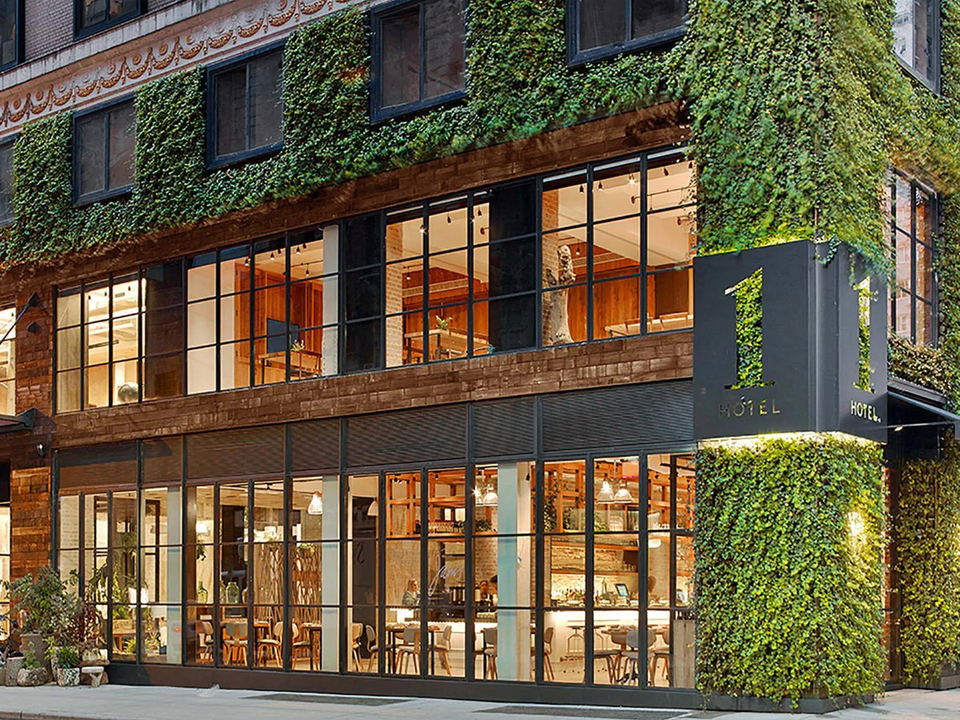 The exterior of 1 Hotel Central Park, featuring a living green wall of climbing plants covering the brick facade, with large industrial-style windows