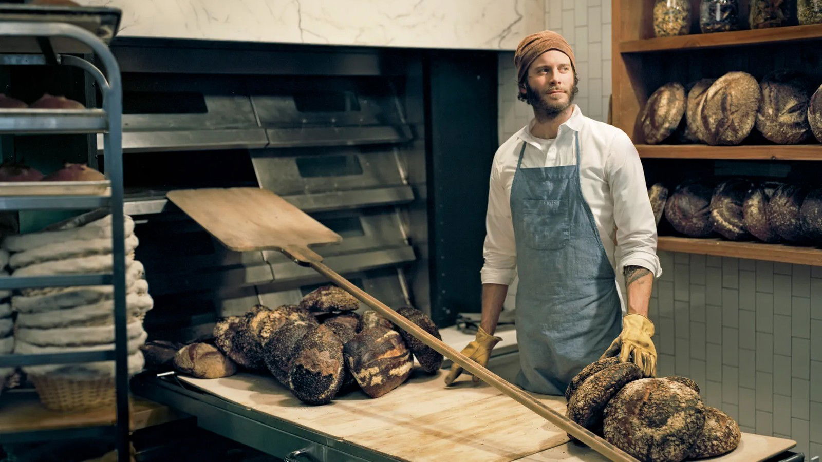 Chad Robertson, the artisan baker, with fresh loaves and a peel in his working bakery.