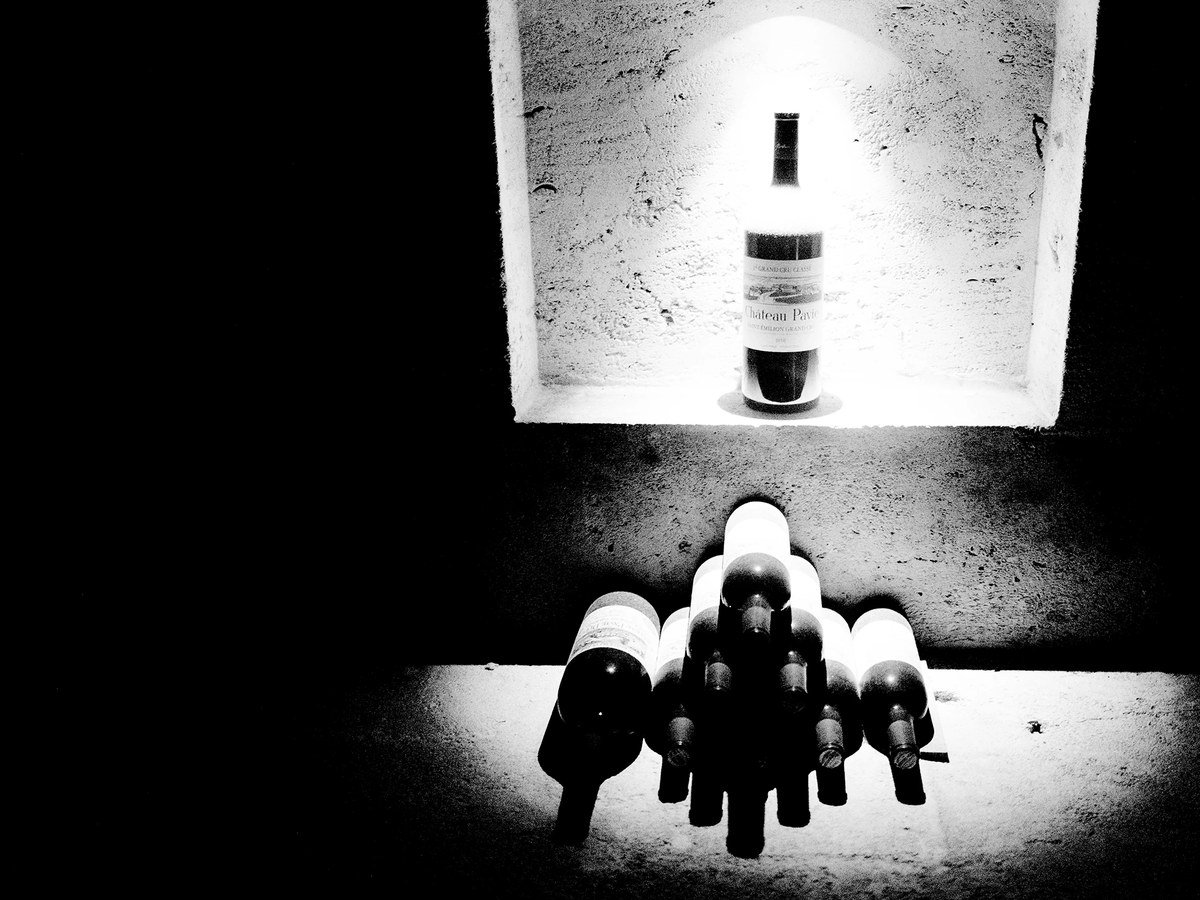 Château Pavie: A bottle stands illuminated in a carved limestone niche above stacked bottles in the underground cellars.