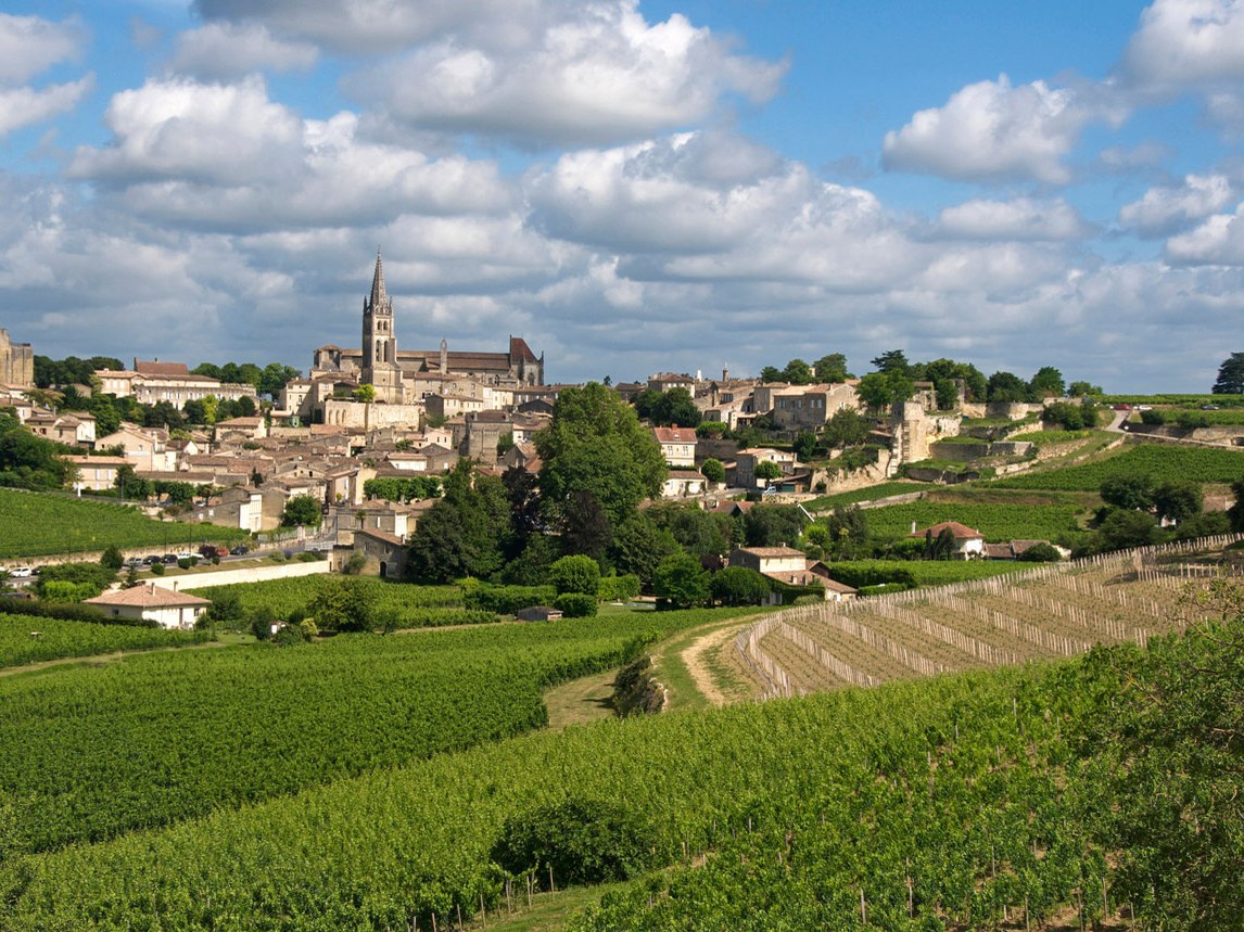 An iconic bell tower rises above the medieval village and surrounding côtes vineyards.