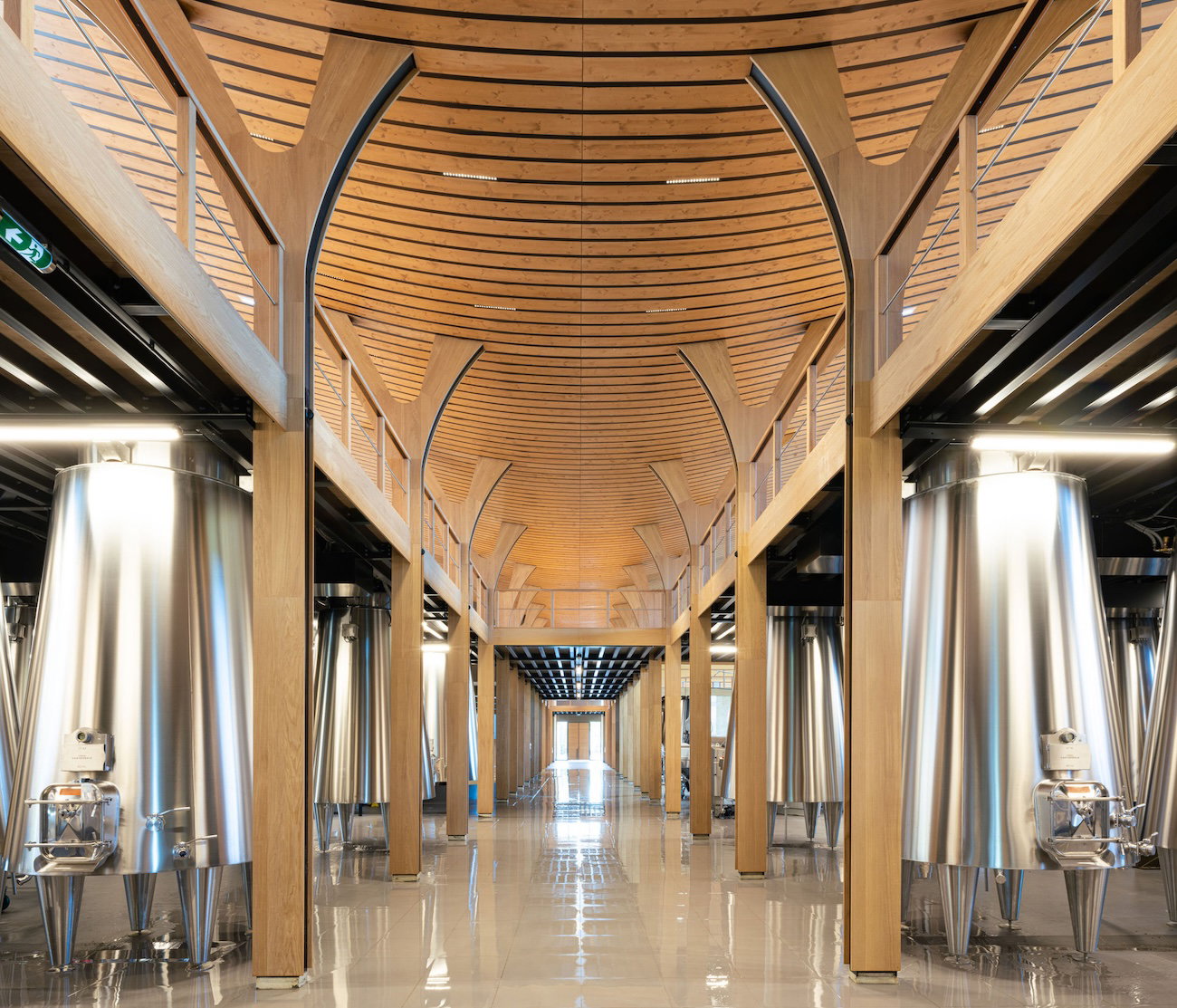 Château Cantemerle's vat room features modern stainless steel tanks under a dramatic curved wooden ceiling.