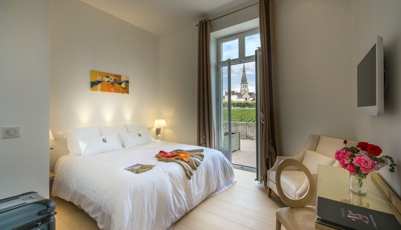 château de cîteaux meursault offers a luxurious room with a terrace overlooking the Côte de Beaune vineyard and a church spire.