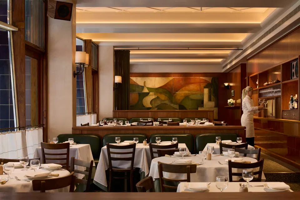 Cote Basque Melbourne's elegant dining room, featuring white-tablecloth tables and green leather banquettes.