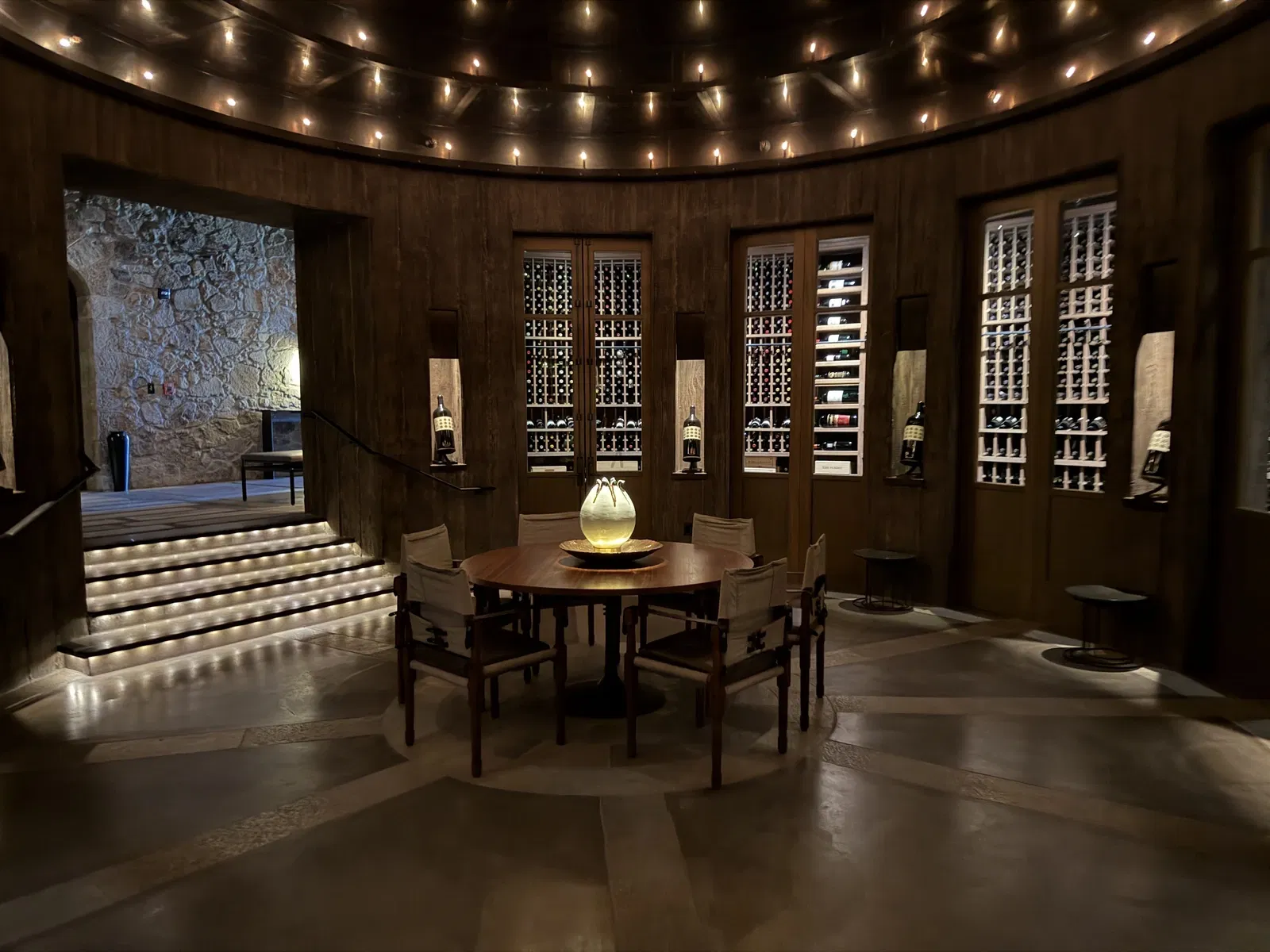 Circular dark-wood wine library with glowing lotus sculpture at Dana Estates