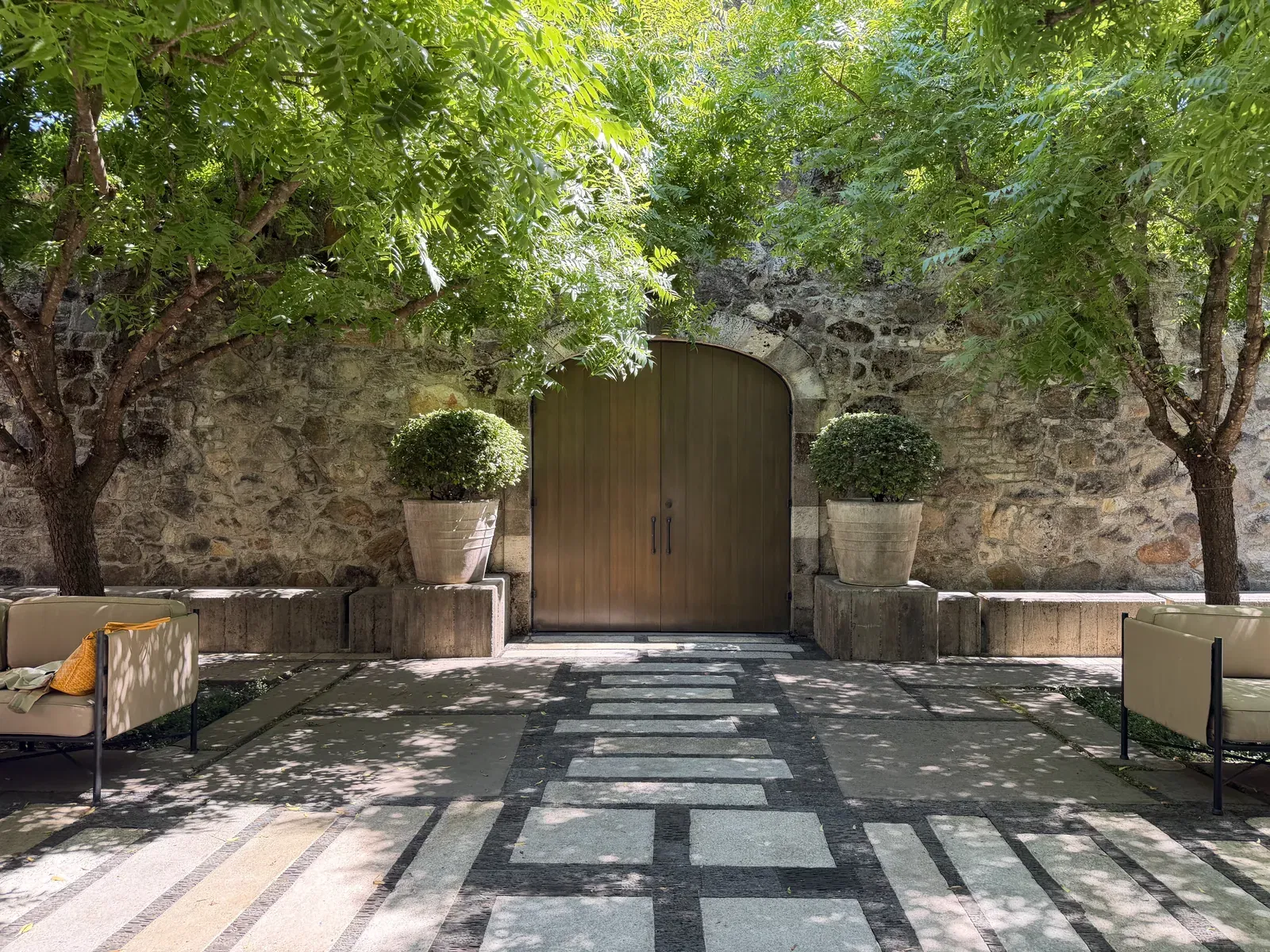 Arched wooden entry doors set into the 1880s stone wall of the DANA Estates courtyard