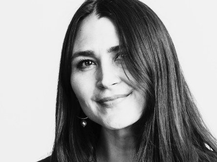 Black and white portrait photograph of a woman with long straight dark hair, smiling slightly at the camera.