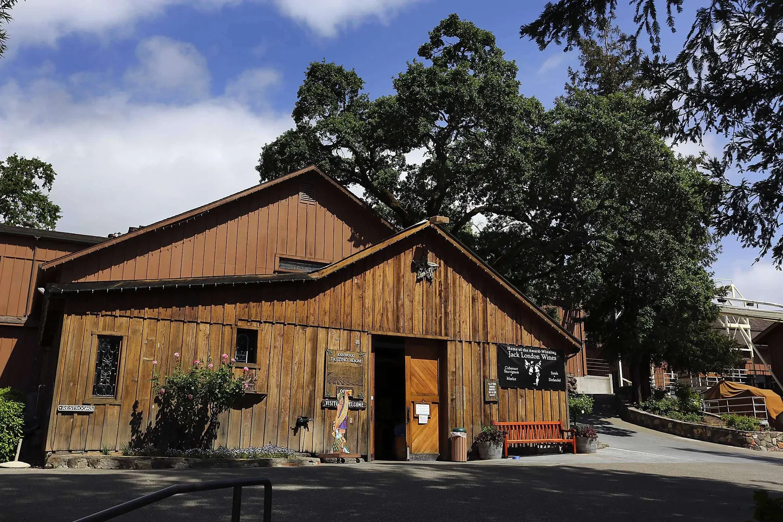 A rustic wooden building with a sign that reads "KENWOOD TASTING ROOM" and another sign for "Jack London Wines."