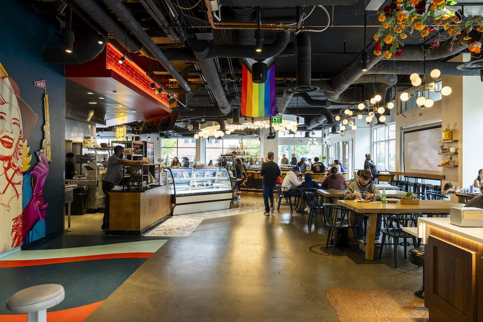 What’s Next for Denver Restaurant Openings features a prominent rainbow flag hanging from the ceiling.