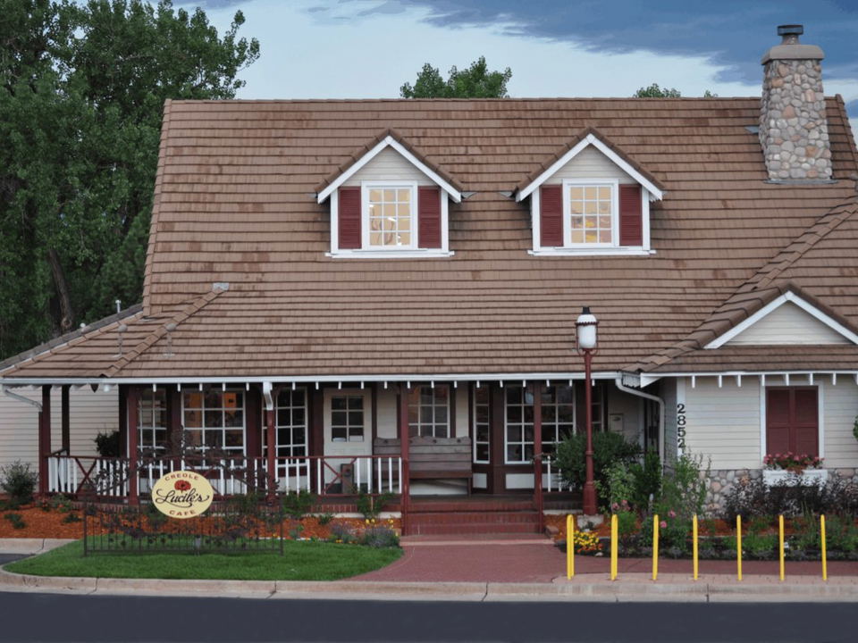 Exterior of Lucile's Creole Cafe, a charming cottage-style building with a covered front porch, dormer windows, and a visible 'Lucile's Creole Cafe'