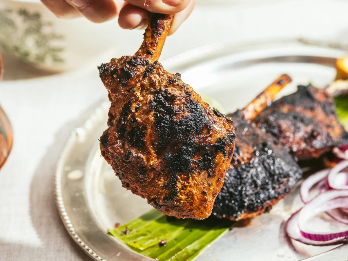 Tandoori-grilled lamb chops with charred exterior on an elegant plated presentation; source page explicitly attests this is Gymkhana's Tandoori Lamb C