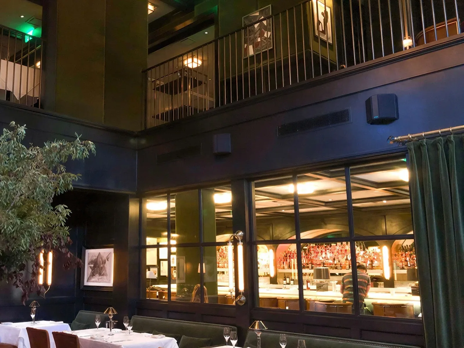 The interior of Selby's Restaurant features a dark, elegant design with a mezzanine level, large windows, and a well-stocked bar.