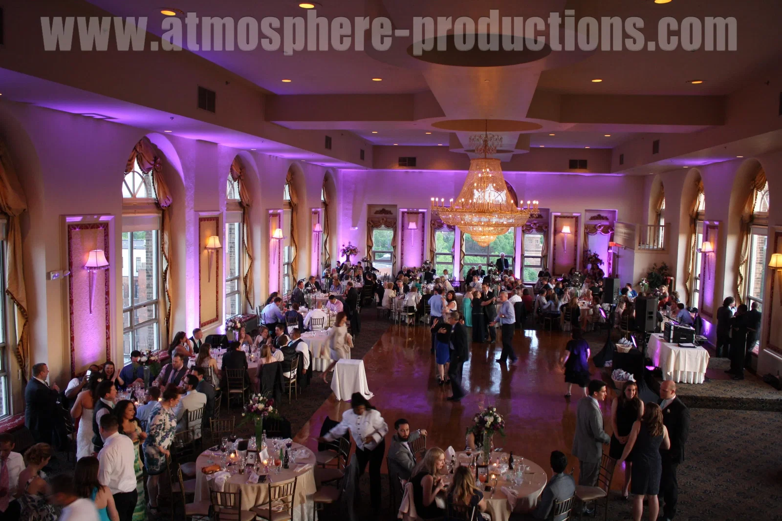 Atmosphere, Service, and Dress Code captures the lively mood within a grand hall illuminated by purple light.