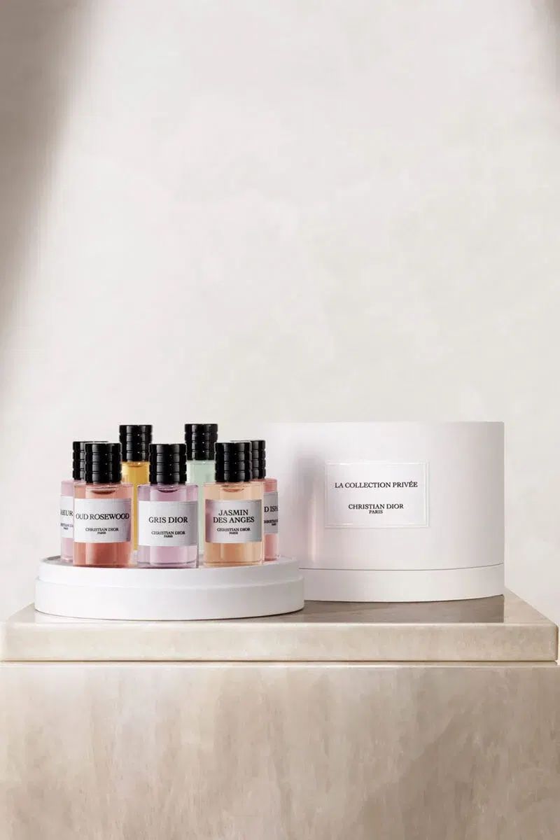 Display of Christian Dior La Collection Privée fragrance bottles arranged on a white circular platform next to a white cylindrical box, matching the s